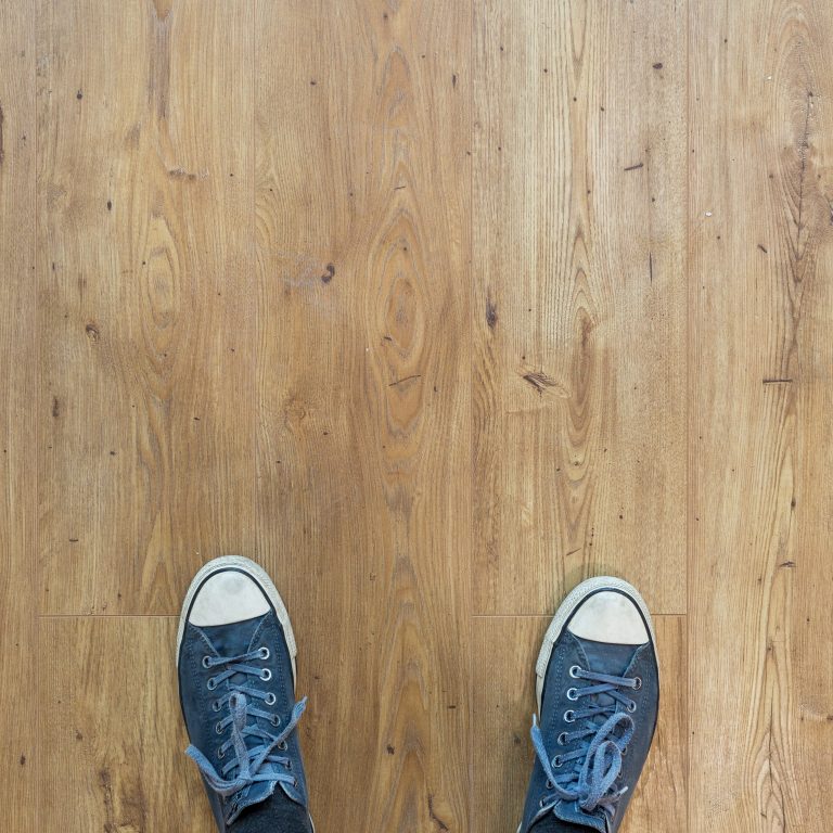 Mann auf Boden schauend. Füsse und Laminat